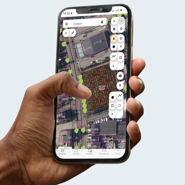 Een mobiele telefoon met daarop de digitale plattegrond van een begraafplaats in de handen van een begraafplaatsbeheerder 