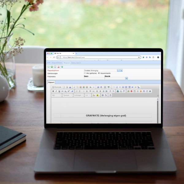 Laptop waarop Eternis software draait op een tafel met een notitieboek, een kopje koffie en een bos bloemen