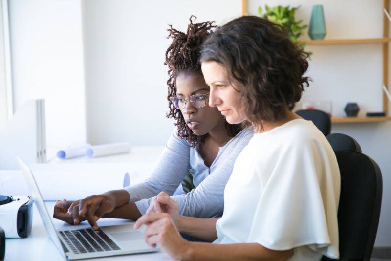 Twee vrouwelijke professionals die samen naar iets op een laptop kijken