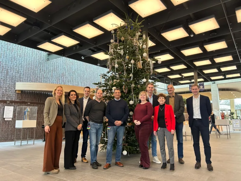 Werknemers van Shift2 en HTA Software die samen bij een kerstboom staan
