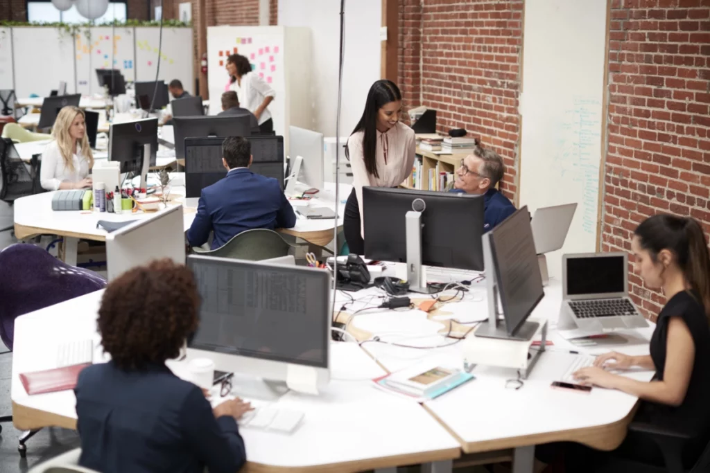 interim-functioneel-applicaiebeheer Een groep professionals die in een kantoortuin met diverse groepen bureaus werkt.